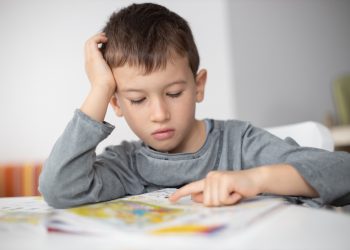 Portrait of young boy struggling with his homework at home. Children education concept